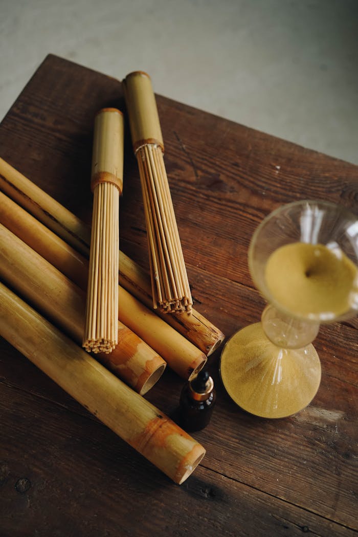 A variety of bamboo massage sticks with oil on a wooden table, perfect for spa and relaxation themes.